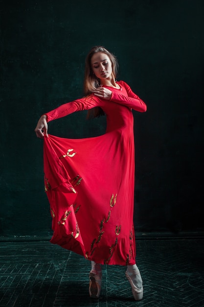 Free photo ballerina posing in pointe shoes at black wooden pavilion