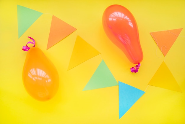 Free Photo balloons and triangle shape paper on yellow background