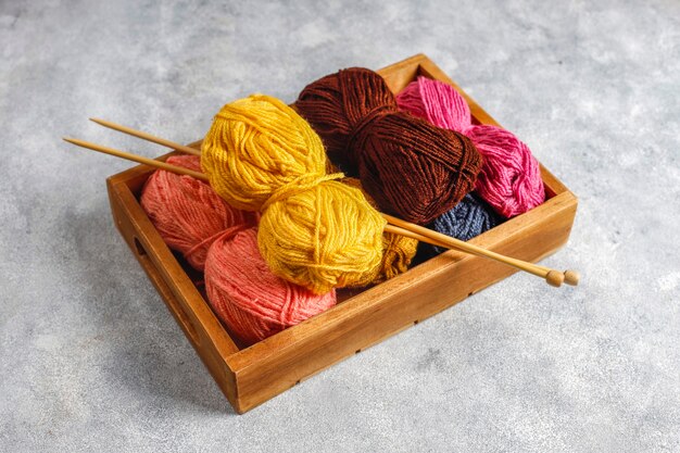 Balls of yarn in different colors with knitting needles.