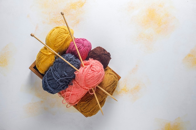 Balls of yarn in different colors with knitting needles.