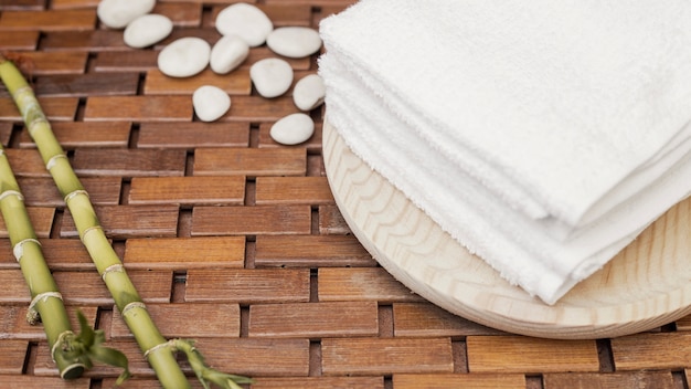 Bamboo plant; towel and pebbles on wooden background