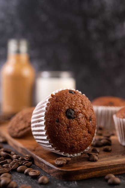 Banana cupcakes that are placed on a wooden plate with coffee grains.