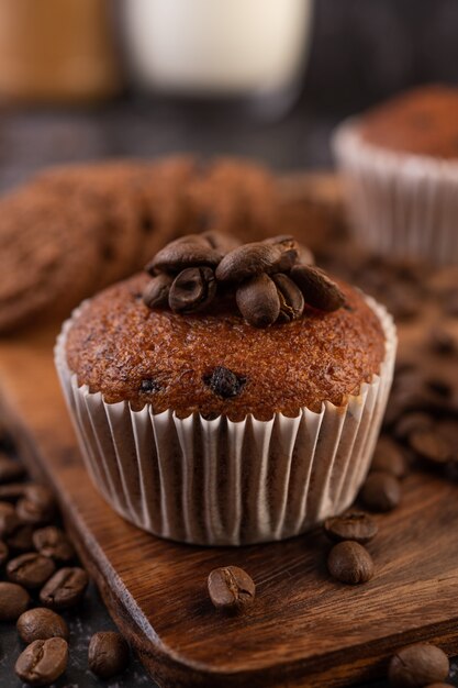 Banana cupcakes that are placed on a wooden plate with coffee grains.