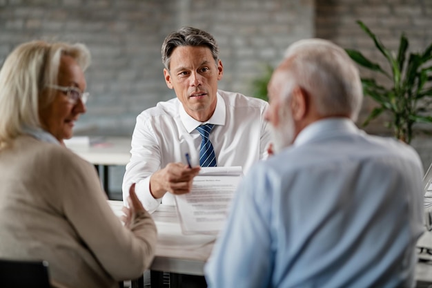 Free photo bank manager showing to a senior couple terms of loan contract while having a meeting in the office