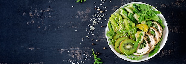 Free photo banner. buddha bowl dish with chicken fillet, avocado, cucumber, fresh arugula salad and sesame.