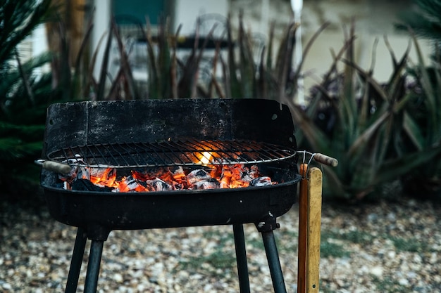 Barbecue burning charcoal in yard of house