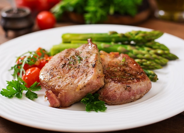 Barbecue grilled beef steak meat with asparagus and tomatoes.