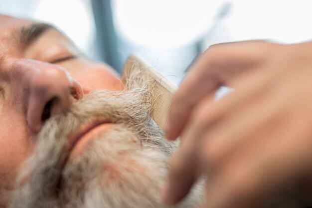 Barber combing mustache to man