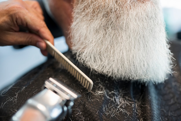 Free Photo barber cutting beard to client in salon