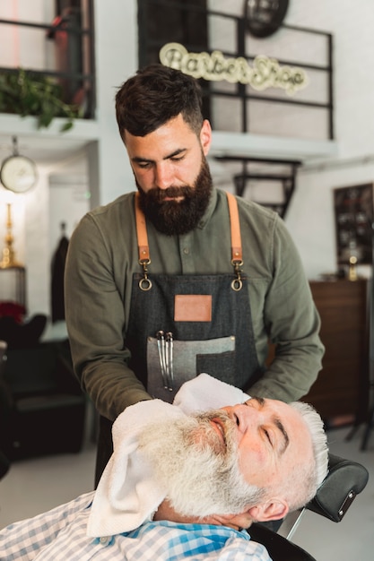 Barber drying old customers face after shaving 