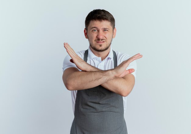 barber man in apron displeased showing stop sign crossing hands standing over white wall