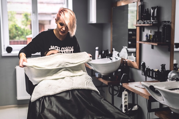 Free photo barber putting towel on face of client