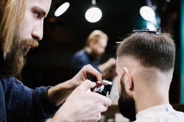 Barber removes man's hair with a clipper