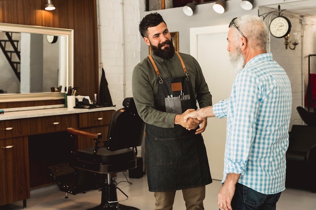 Free photo barber and senior male client shaking hands