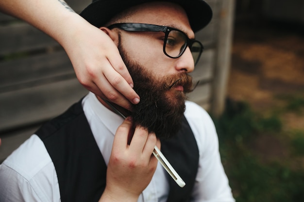 Barber shaves a bearded man in vintage atmosphere