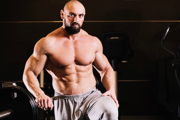 Free Photo bare-chested man posing near barbell