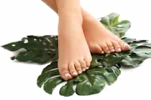 Free photo bare feet on leaves. foot care and pedicure concept