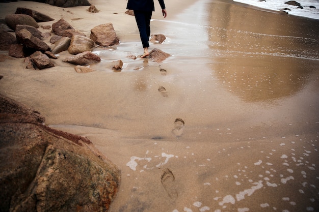 Free Photo barefoot man is walking across the beach leaving traces behind