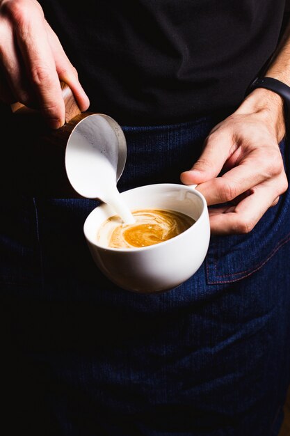 Barista is preparing cappuccino with milk foam