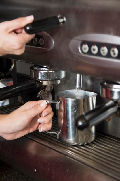 Barista taking hot water from tap in the mug