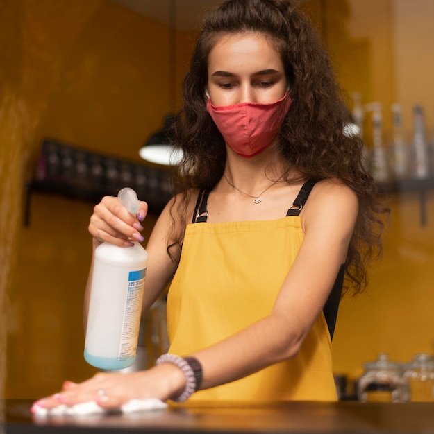 Free Photo barista wearing a medical mask while cleaning in the coffee shop