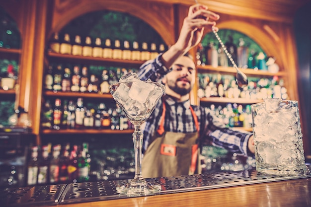 Free photo the barman making an alcoholic cocktail at the bar counter on the bar space