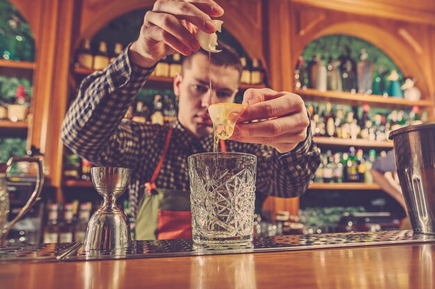 Barman making an alcoholic cocktail at the bar counter on the bar