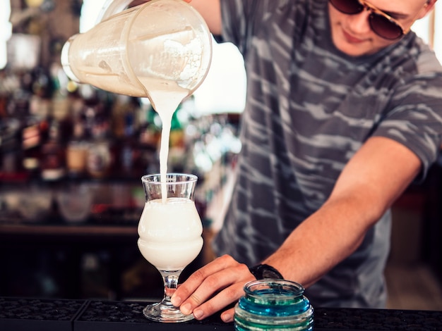 Barman pouring milkshake in glass