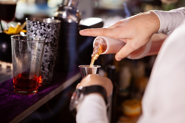 Barman in white shirt pouring drink incredient for cocktail