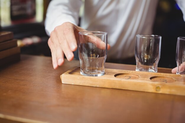 Bartender arranging beer glass on tray at bar counter