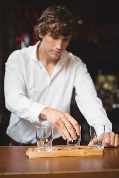 Bartender arranging beer glass on tray at bar counter