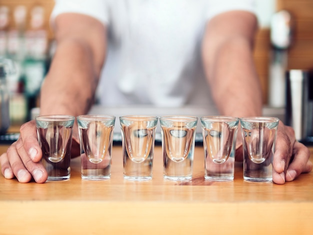 Bartender placing line of shot glasses on counter