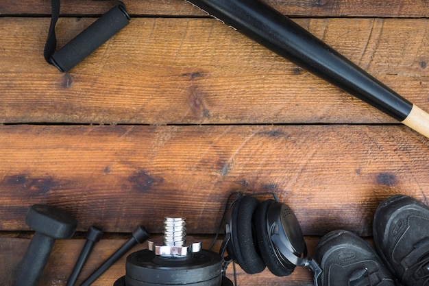 Free Photo baseball bat; fitness strap; dumbbells; skipping rope; weights; headphone and shoes on wooden textured background