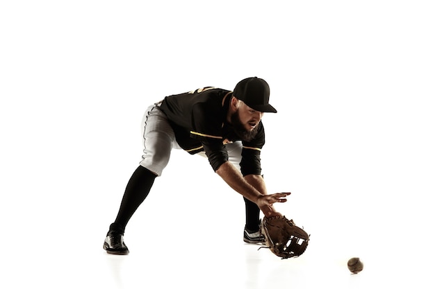 Baseball player, pitcher in a black uniform practicing and training isolated on a white wall. Young professional sportsman in action and motion. Healthy lifestyle, sport, movement concept.