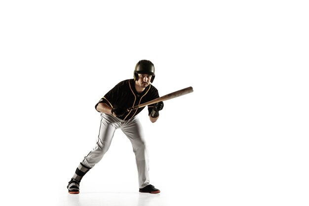 Baseball player, pitcher in a black uniform practicing and training isolated on a white wall. Young professional sportsman in action and motion. Healthy lifestyle, sport, movement concept.