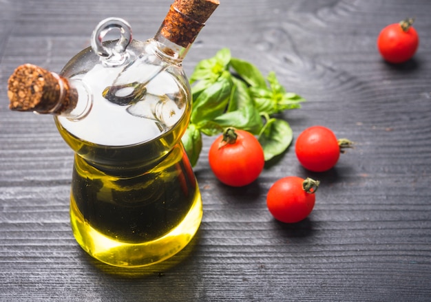 Free photo basil leaves; tomatoes and bottle of olive oil with cork stopper