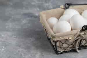 Free photo basket full of fresh white chicken eggs on a marble background .