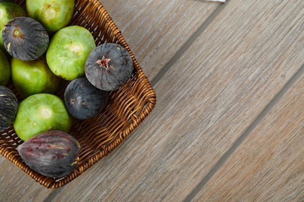 Free photo a basket of ripe figs on wooden table.