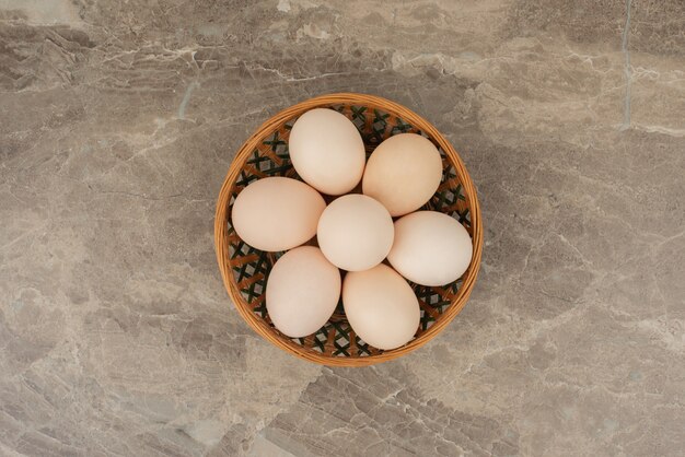 Basket of white eggs on marble table .