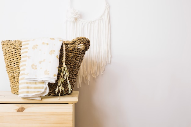 Basket with blankets near wall decoration