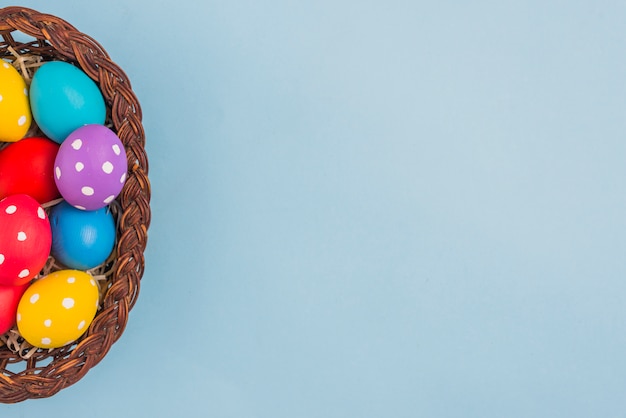 Basket with Easter eggs on blue table