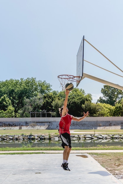 Basketball player throwing ball in the hoop at outdoors court