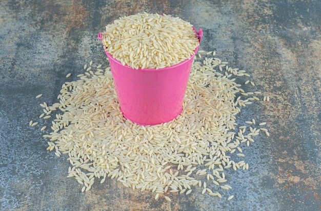 Free Photo basmati rice spilled from a bucket, on the marble surface.