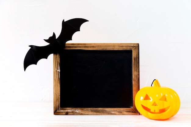 Bat and jack-o-lantern near chalkboard