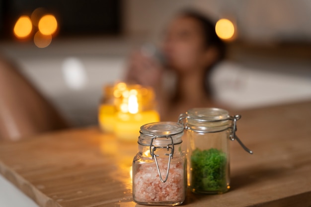 Free photo bath salts and candles with defocused woman taking a bath