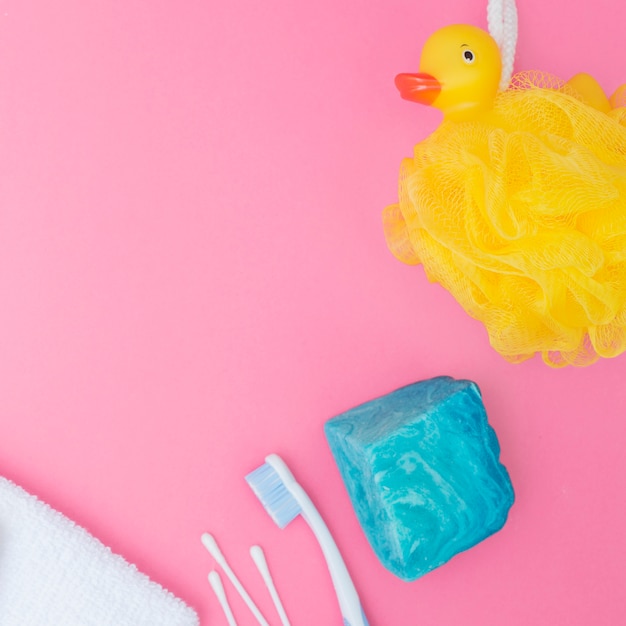 Bath sponge; soap; cotton swab and towel on pink backdrop