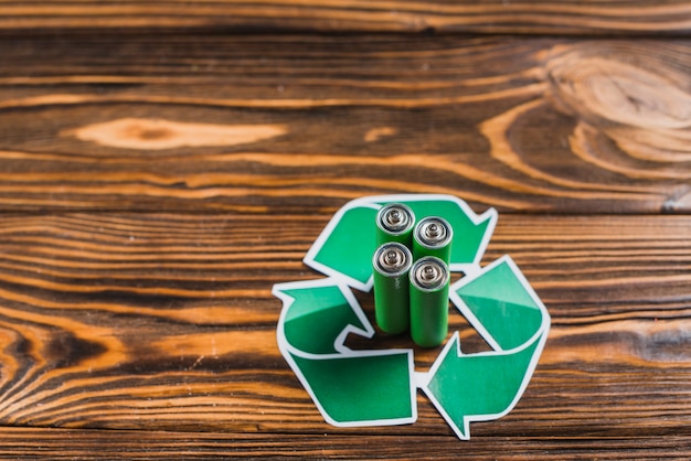 Free Photo battery in the recycle icon on wooden textured backdrop