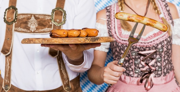 Free photo bavarian man and woman holding oktoberfest snacks