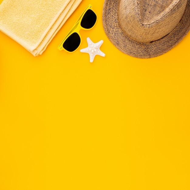 Beach accessories on the yellow background. Starfish, sunglasses, towel and striped hat. 