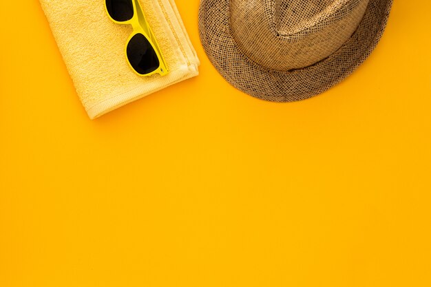 Beach accessories on the yellow background. Sunglasses, towel. flip-flops and striped hat. 